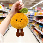 Apricot plush keychain charm with leaf and corduroy legs held in a store aisle