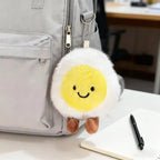Fluffy boiled egg plush charm clipped to a gray backpack zipper