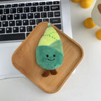 Bamboo shoot plush keychain charm with smiling face on a wooden tray