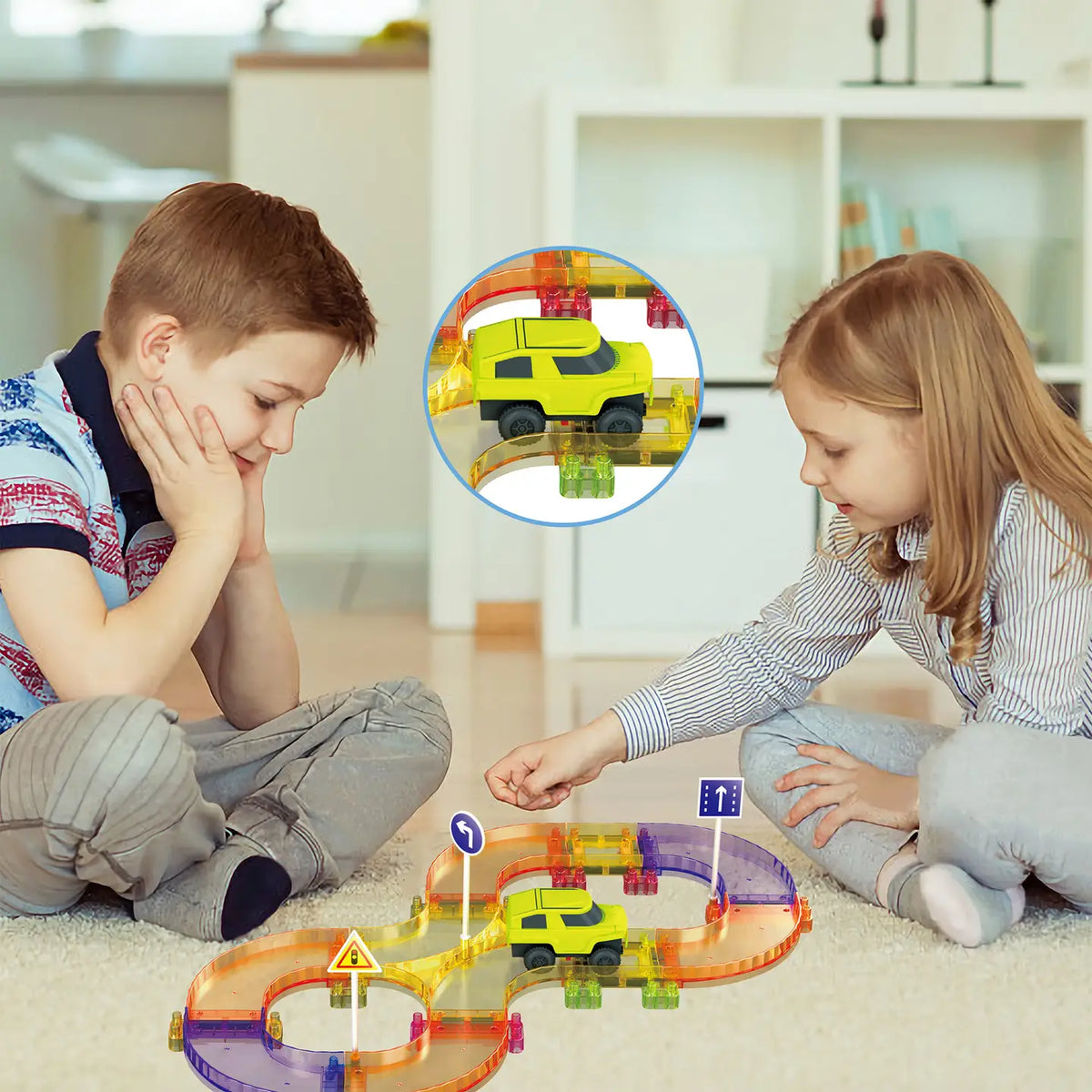 Two kids playing on the floor with a PicassoTiles magnetic tile race track and green toy car