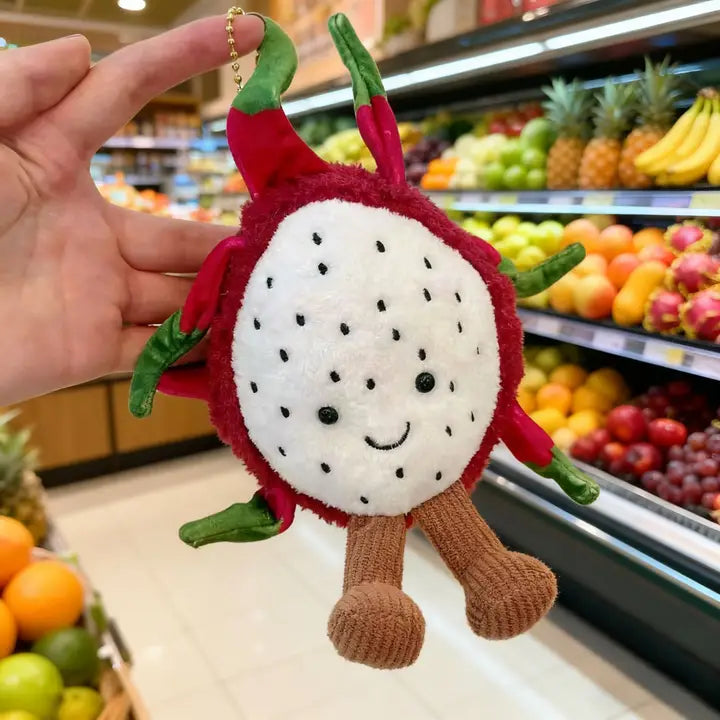 Dragon fruit plush keychain charm with corduroy legs held in a hand