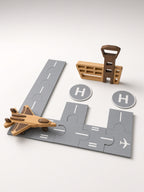 Wooden airport playset: gray puzzle runway pieces, wooden jet, control tower, and helipads