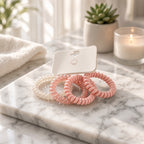 Spiral coil hair ties in cream and light pink shades on a card
