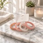 Pink, cream, and multicolor spiral coil hair ties on a marble surface