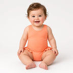 Baby wearing a coral tank one-piece swimsuit with ruffle hips