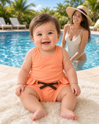 Baby wearing coral tie-waist shorts poolside