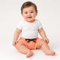 Baby wearing coral tie-waist summer shorts with a white tee