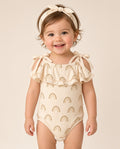 Baby wearing a cream rainbow print ruffle tie-shoulder romper with headband