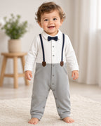 Toddler wearing a baby tuxedo snap romper with navy bow tie, faux suspenders, and gray legs