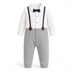 Baby tuxedo romper with white collared top, navy bow tie and suspenders, and gray snap legs, front view