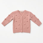 Pink knit baby cardigan with bobble pom-pom texture and buttons, flat view