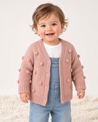 Toddler wearing a pink bobble knit cardigan over a white tee and overalls