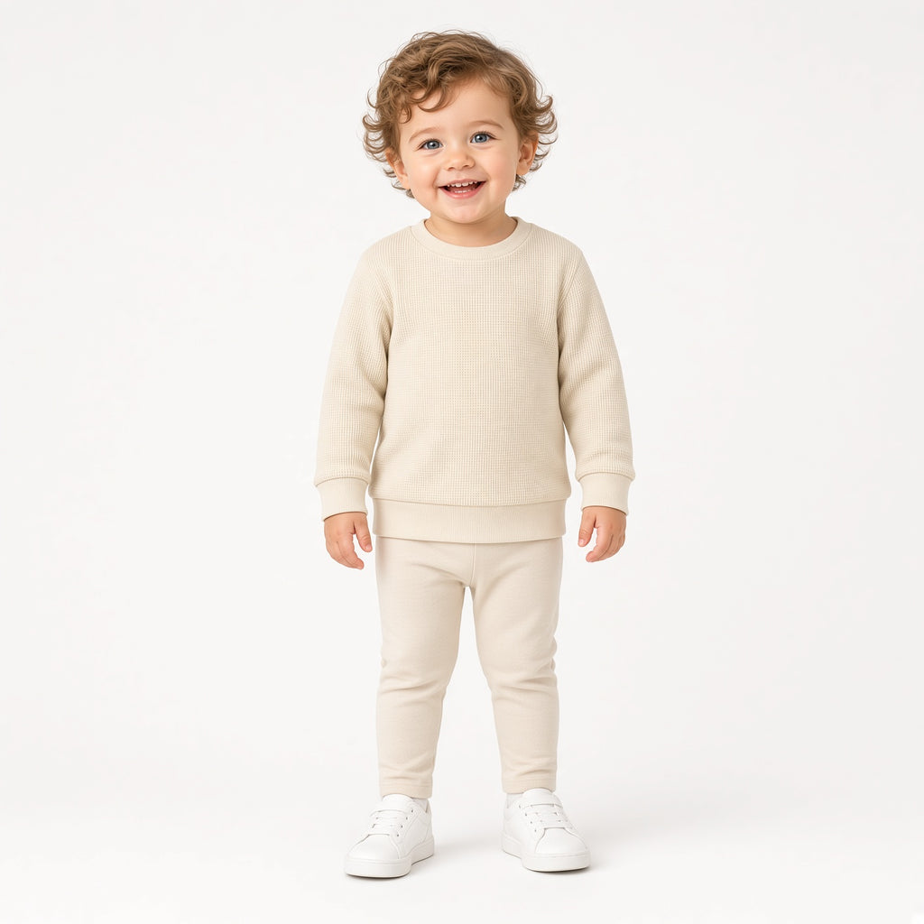 Toddler wearing a cream waffle knit long-sleeve crewneck with cream pants