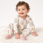 Baby sitting in a cream carnival Ferris wheel print footed sleeper with pink cuffs