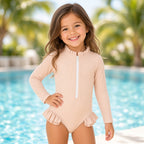 Girl wearing a beige long-sleeve ribbed zip leotard with ruffle trim by a pool