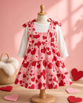 Heart print tiered pinafore dress with tie shoulders on a child dress form