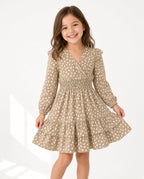 Girl wearing a tan spot print smocked wrap dress with ruffle tiers