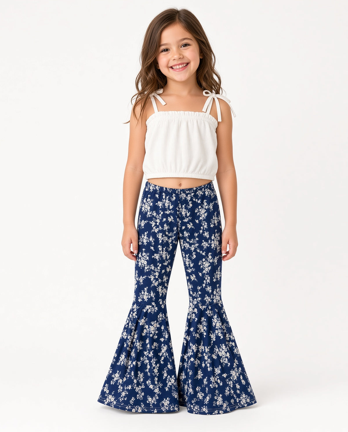 Girl wearing a white tie-strap crop top and navy floral bell-bottom pants