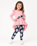Girl wearing a pink high-low tunic with bow and navy daisy print leggings
