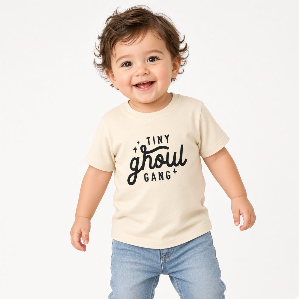 Toddler wearing a cream Tiny Ghoul Gang Halloween tee with jeans