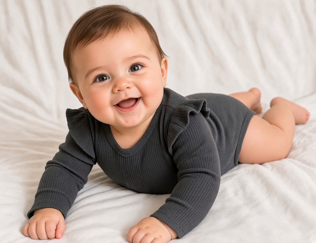 Baby lying on tummy in a charcoal gray ruffle long-sleeve bodysuit