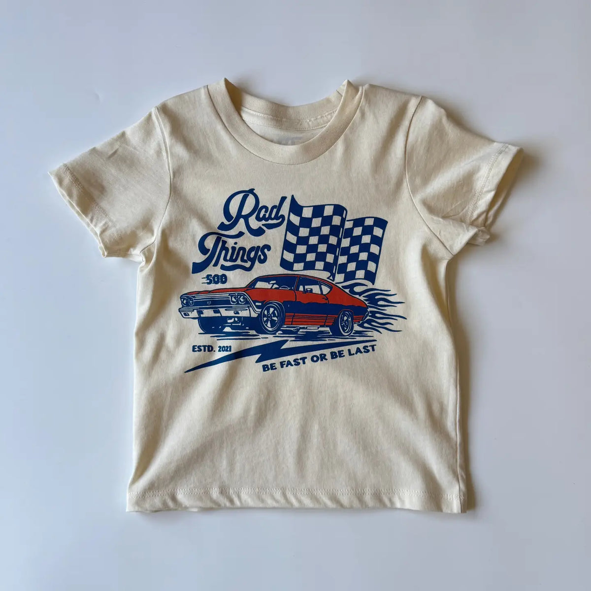 Cream kids graphic tee with Rad Things race car and checkered flag print, angled view