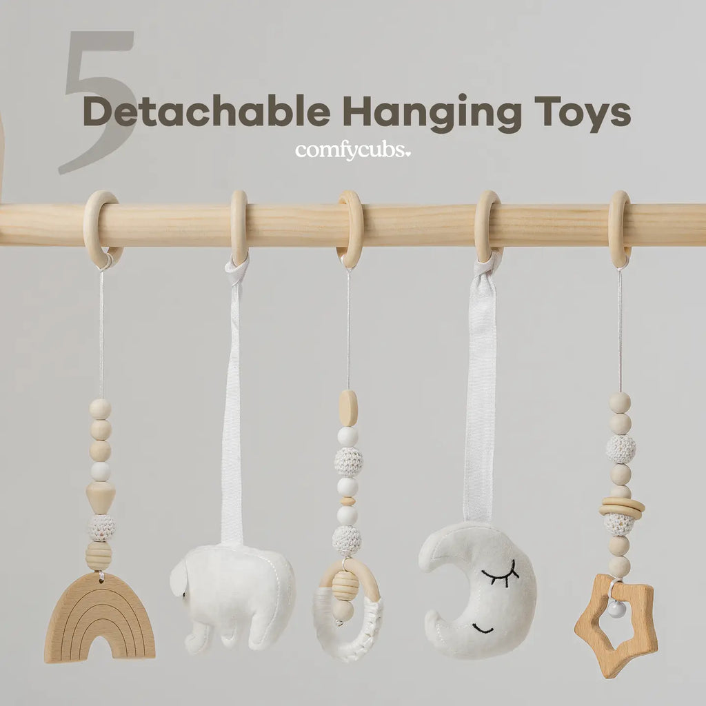 Close-up of five detachable hanging toys on the wooden play gym bar, including rainbow, moon, and star