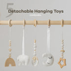 Close-up of five detachable hanging toys on the wooden play gym bar, including rainbow, moon, and star