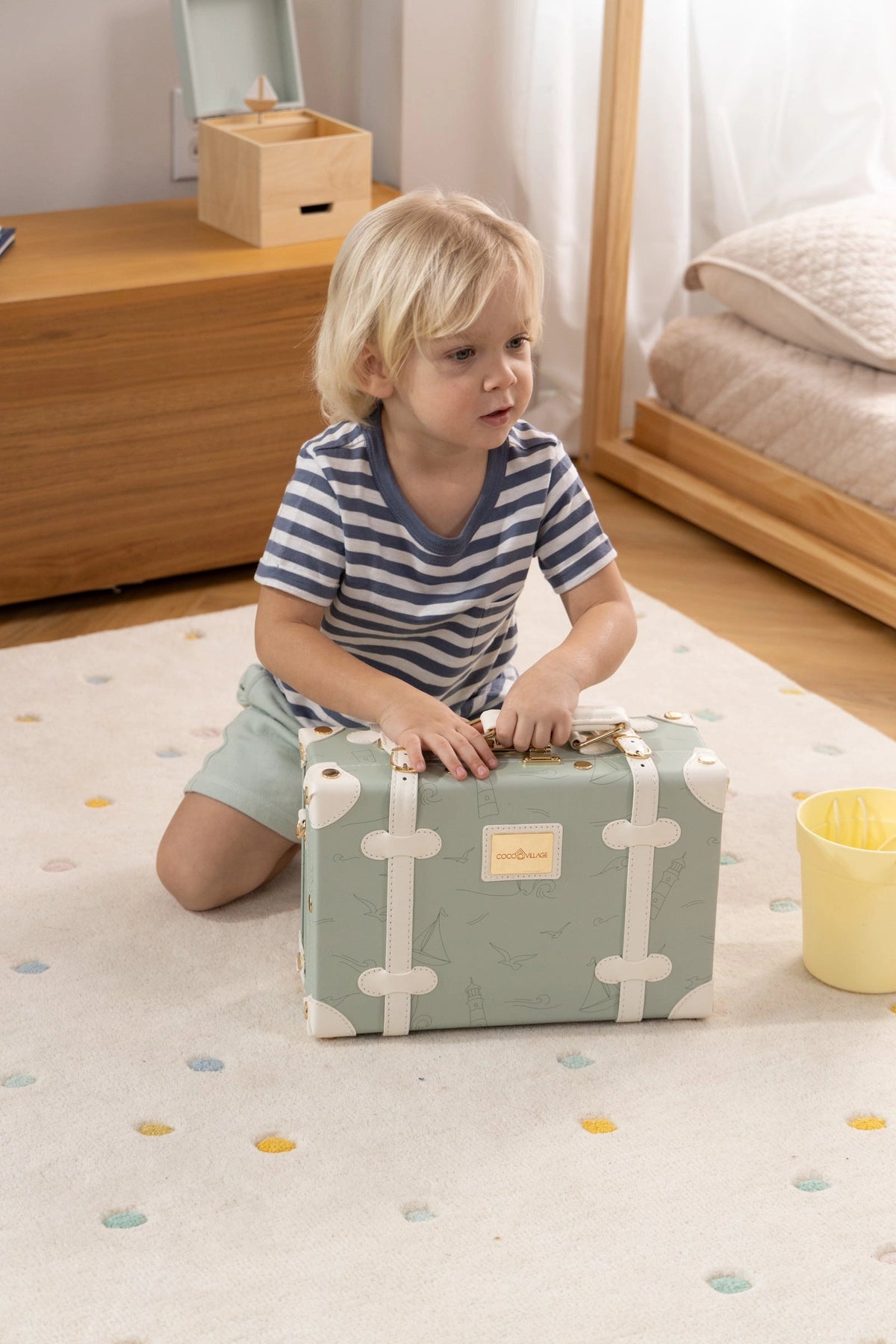 Child carrying the Coco Village ocean green vegan leather play suitcase