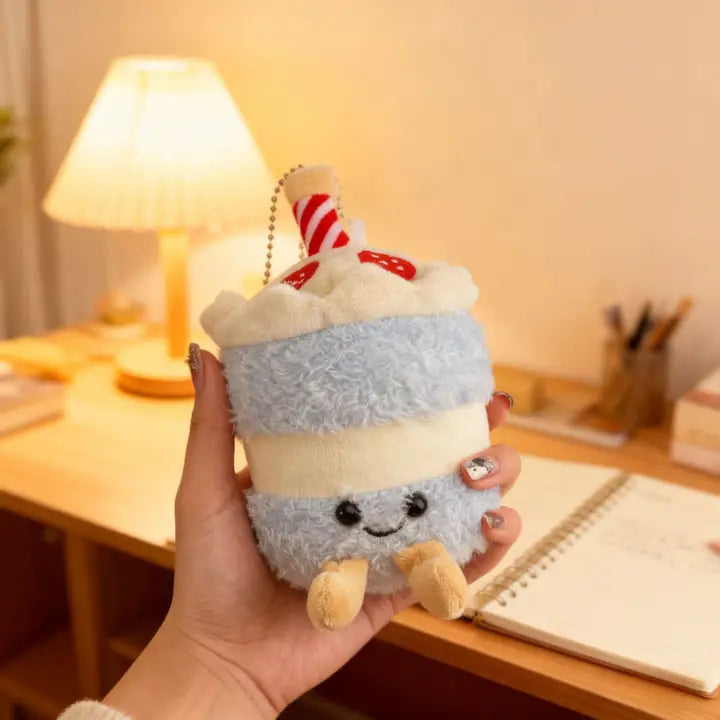 Blue birthday cake plush charm with candle held in a hand