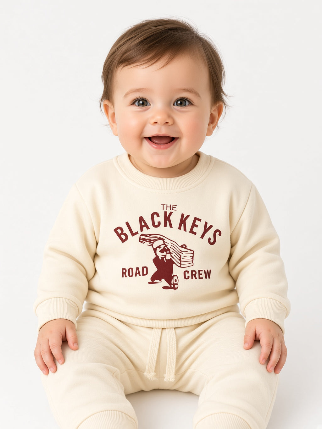 Baby wearing a beige The Black Keys Road Crew sweatshirt and matching pants