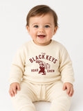 Baby wearing a beige The Black Keys Road Crew sweatshirt and matching pants