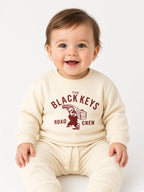 Baby wearing a beige The Black Keys Road Crew sweatshirt and matching pants