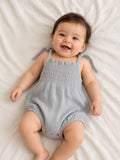 Baby wearing a gray smocked Libby bubble romper with tie shoulder straps