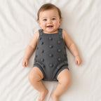 Baby wearing a gray knitted romper with bobble texture