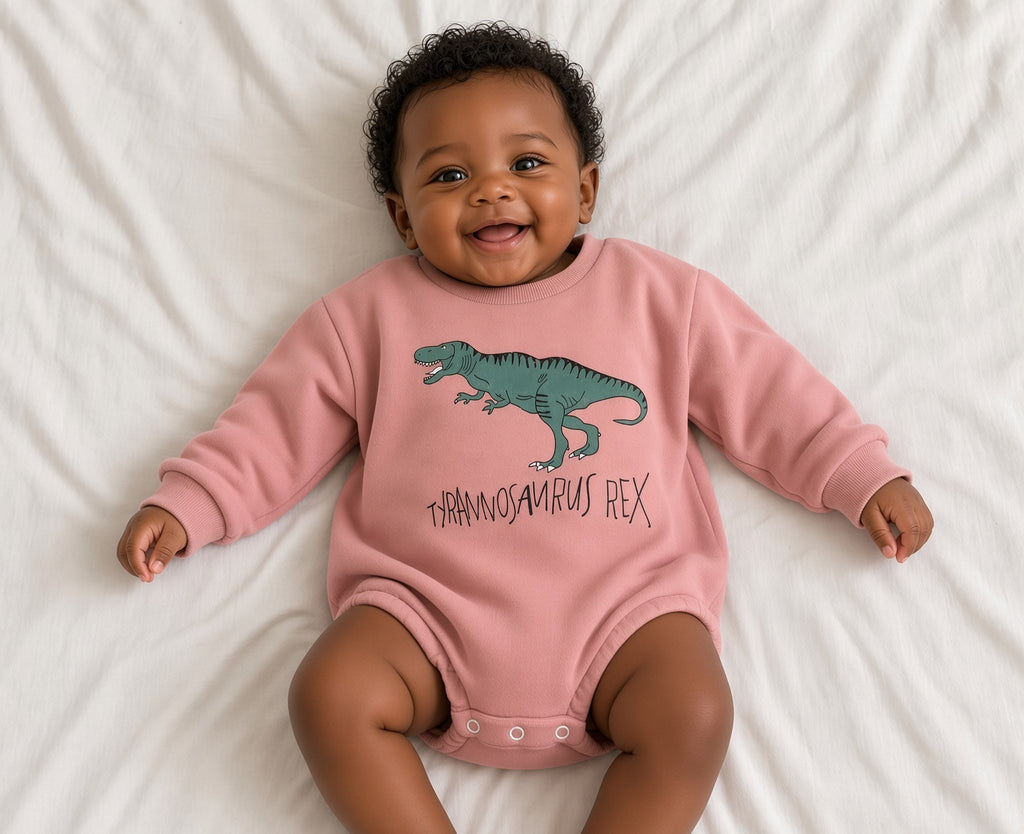 Baby wearing a pink T-Rex romper with green dinosaur graphic