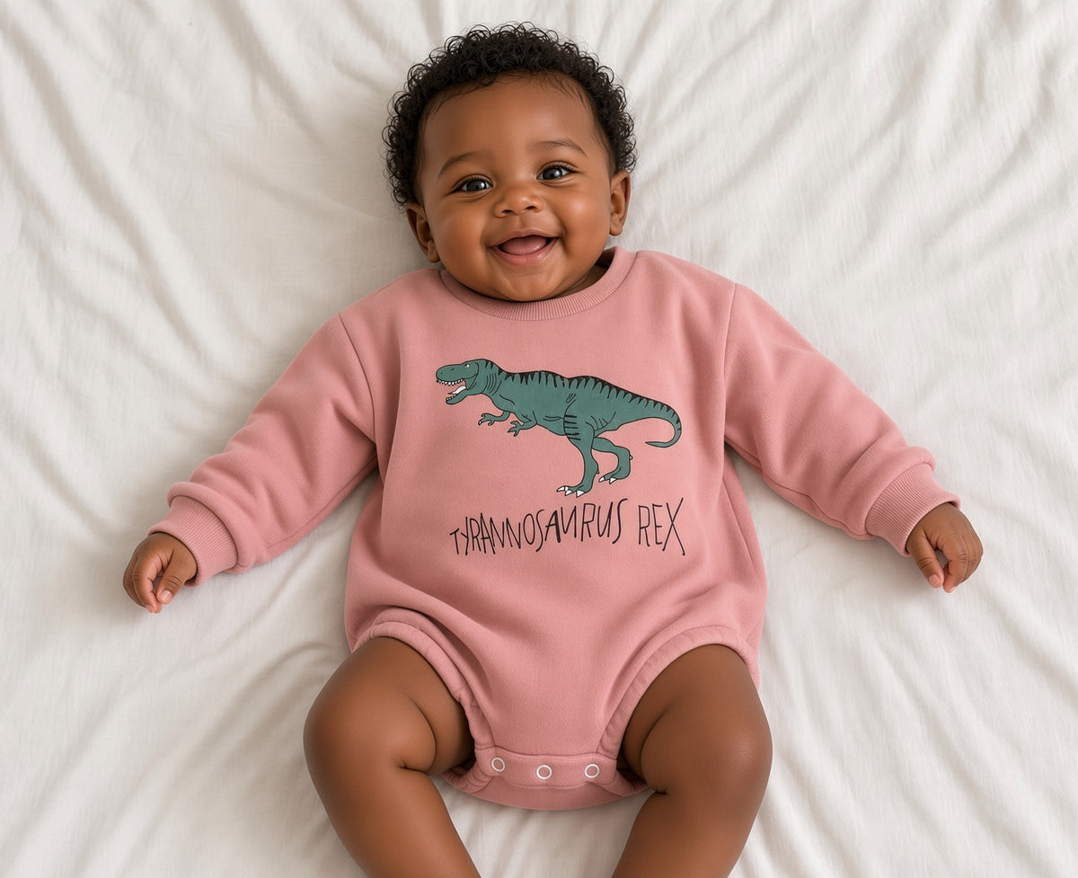 Baby wearing a pink T-Rex romper with green dinosaur graphic