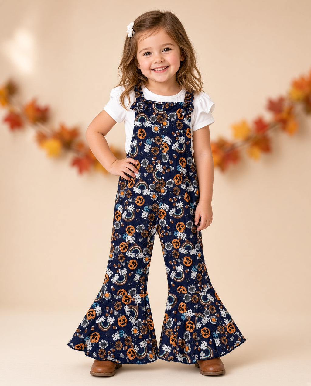 Girl wearing a navy Halloween pumpkin print bell-bottom jumpsuit with ruffle straps