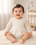 Baby wearing a white lace long-sleeve romper with bow clip