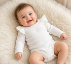 Baby in a white long-sleeve ruffle bodysuit with snap bottom
