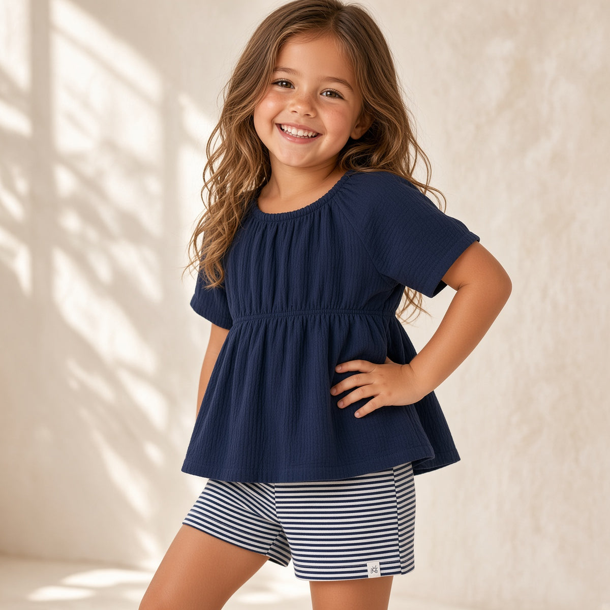 Girl wearing a navy dotted muslin top with navy and white striped shorts
