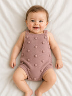 Baby wearing a dusty rose knitted bobble romper