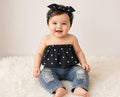 Baby wearing a black polka dot tube top, distressed jeans, and matching bow headband