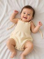 Baby wearing a pale yellow smocked Libby bubble romper with tie straps