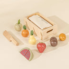 Wooden play fruits including watermelon, strawberry, pear, and orange with crate and knife