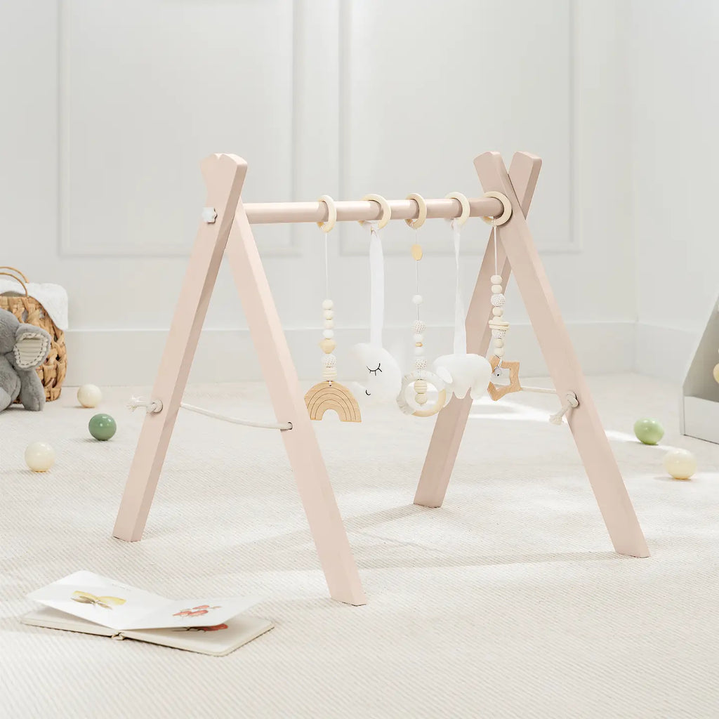 Comfy Cubs natural pine A-frame baby play gym with five hanging toys in a bright nursery