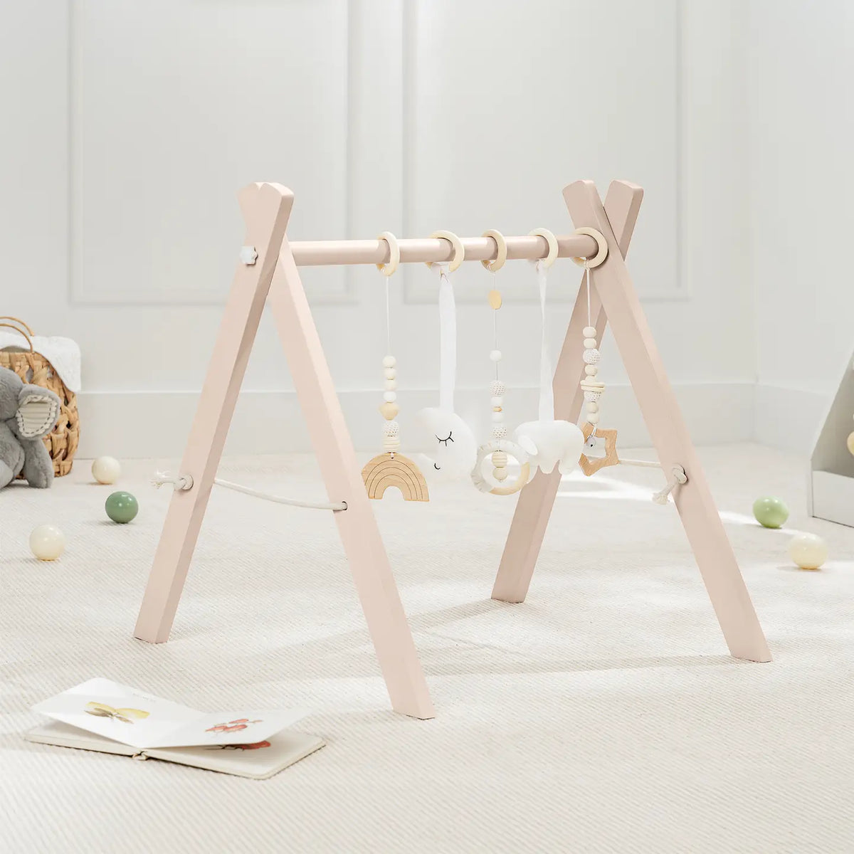Comfy Cubs natural pine A-frame baby play gym with five hanging toys in a bright nursery